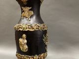 a black vase with a gold decoration on it