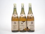 trois bouteilles de vin posées les unes à côté des autres sur une surface blanche