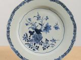 a blue and white plate with a bird and flowers on it