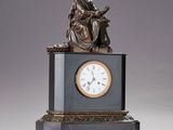 une statue d'un homme assis au sommet d'une horloge