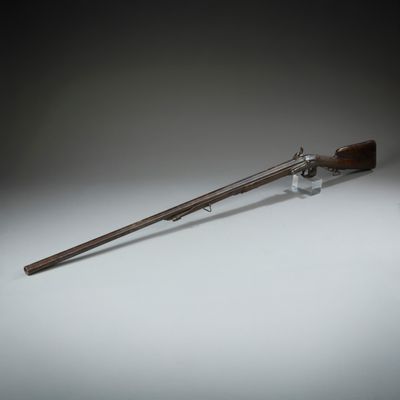 un vieux pistolet avec une poignée en bois sur une surface blanche