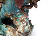 a figurine of a dog with a dragon on it ' s back