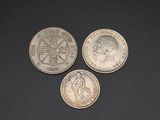 three silver coins sitting on top of each other on a black surface