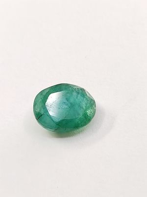 a close up of a green emerald stone on a white surface