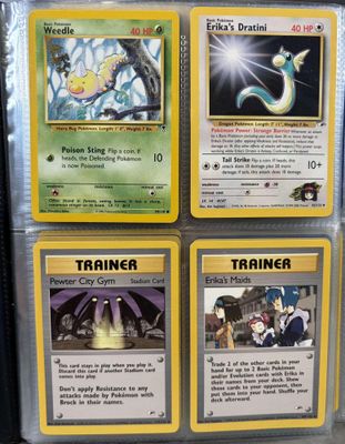 Quatre cartes Pokémon différentes sont exposées dans une vitrine.