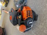 an orange and black lawn mower sitting on the ground