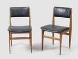 pair of chairs with black leather upholstered seats on a white background