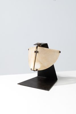 sculpture en bois représentant un bateau, posée sur un socle noir, sur une surface blanche