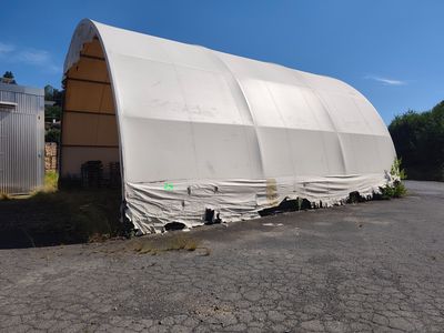 une grande tente blanche installée au milieu d'un parking