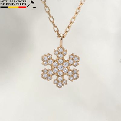 a close up of a snowflake pendant on a gold chain