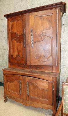 une armoire en bois munie d'une porte, devant laquelle se trouve une chaise