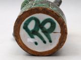 a close up of a green and white vase on a white surface