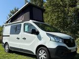 une camionnette blanche garée dans un champ, avec une tente posée dessus