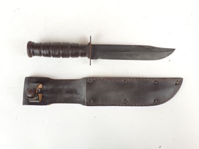 pair of knives with leather sheaths on a white surface