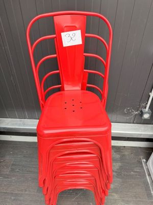 a stack of red chairs in front of a gray wall