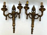 three antique brass wall sconces with candles on each of them