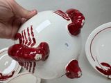 a person holding a red and white piggy bank with red paint on it