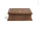an old wooden box with carvings on it sitting on a white surface