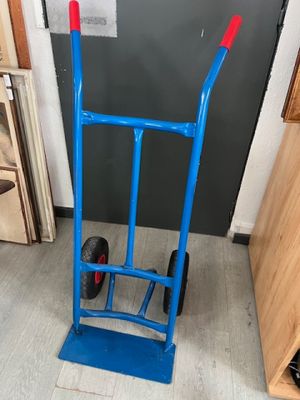 un diable bleu avec une poignée rouge dans une pièce