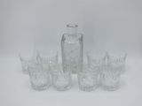 six glasses and a decanter sitting on a table
