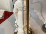 pair of white porcelain figurines of a man and a woman on a pedestal