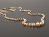 a close up of a pearl necklace on a black surface