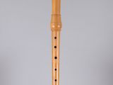 a wooden flute on a stand on a white surface