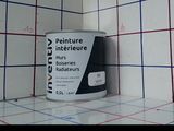 un pot de peinture posé sur un mur carrelé
