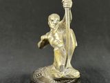 an old bronze figurine of a man with a staff on a rock