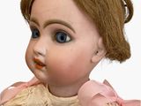 a close up of a doll with a pink dress on