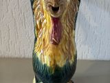 une figurine en céramique représentant un coq posée sur une table