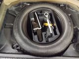a tire in the trunk of a car with tools in it