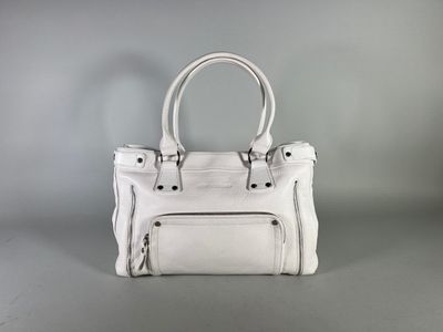 a white handbag sitting on top of a gray surface