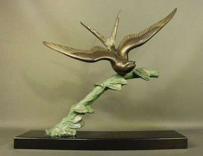 une sculpture en bronze représentant un oiseau perché sur une branche