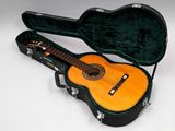 une image représentant une guitare dans son étui, posée sur une surface blanche