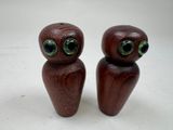 paire de figurines en bois représentant des chouettes aux yeux verts sur fond blanc