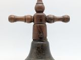a small bell with a wooden cross on top of it