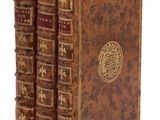trois vieux livres sont empilés sur une surface blanche