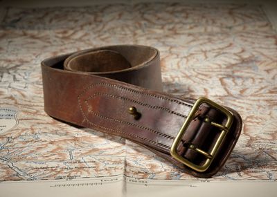 une ceinture marron avec une boucle en laiton posée sur une carte