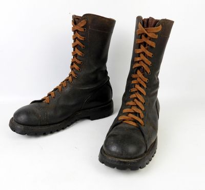 une paire de bottes en cuir noir avec des lacets marron sur fond blanc