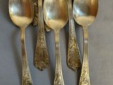 six spoons and a spoon rest on a table with silverware