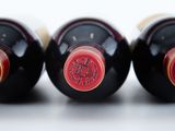 three bottles of wine are lined up in a row on a white surface