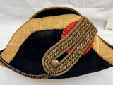 un chapeau noir et doré orné d'un ruban rouge