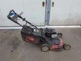 an image of a lawn mower parked in front of a garage
