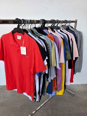 a lot of shirts hanging on a rack in a room