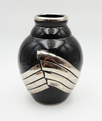 un vase noir orné de rayures argentées sur fond blanc