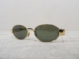 gold sunglasses with green lenses on a white surface