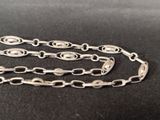 a close up of a silver chain on a black surface