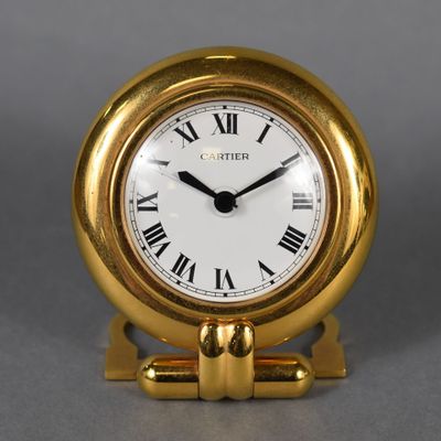 a small gold clock with roman numerals on it