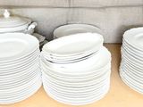 many plates and cups stacked on a shelf in a kitchen